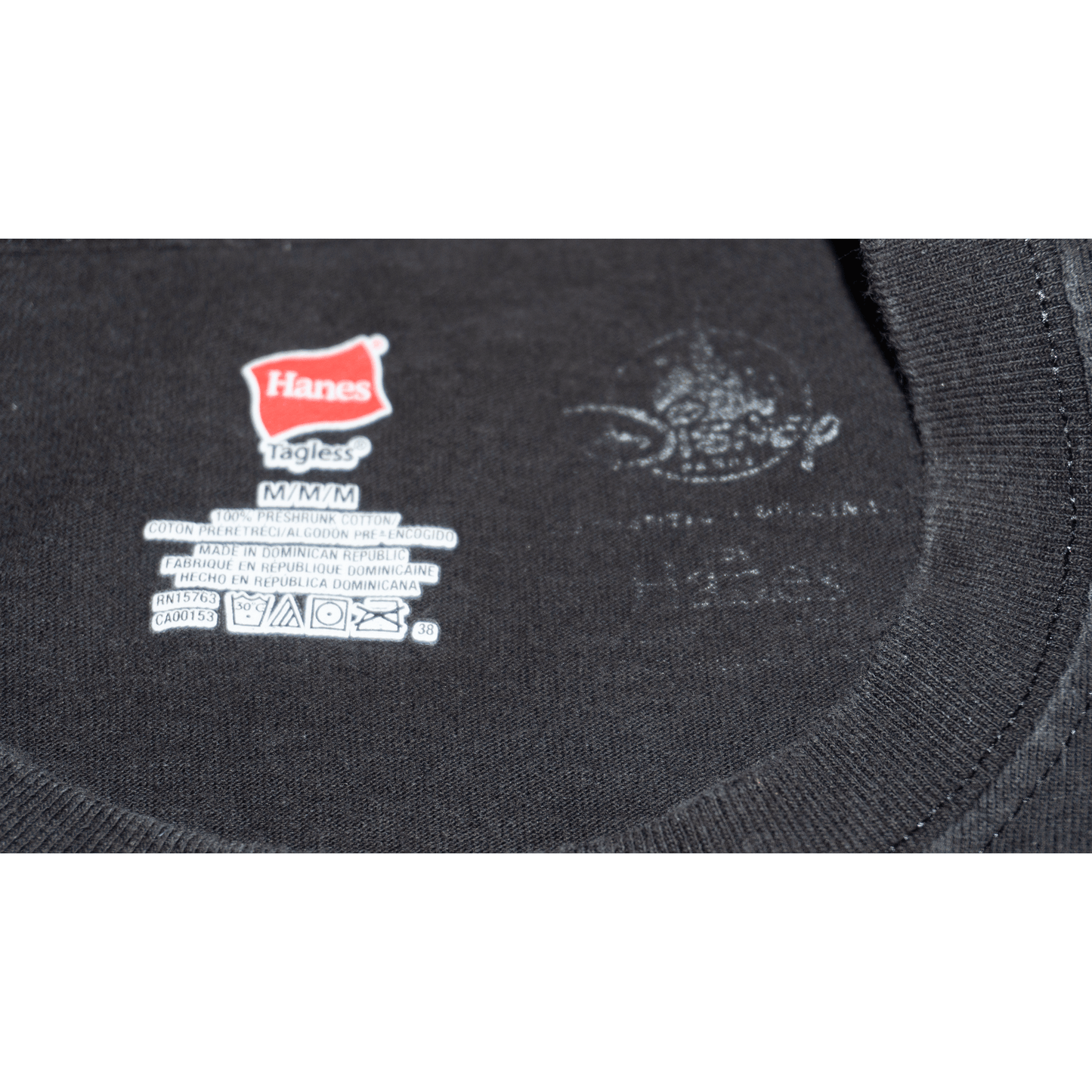 Hanes tag on a black Disney T-shirt, showing size M and care instructions, with a tagless design.