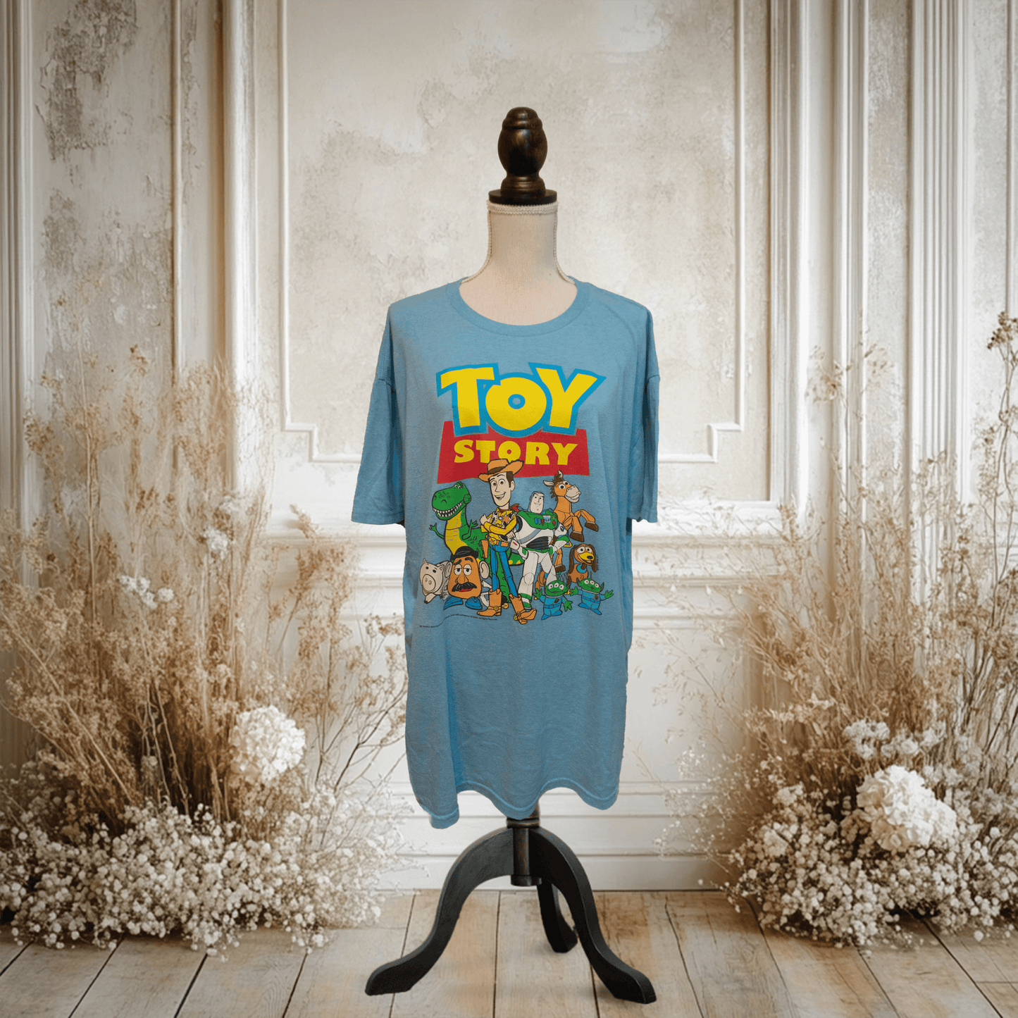 トイストーリーのキャラクターがプリントされた青いTシャツがディスプレイされている画像